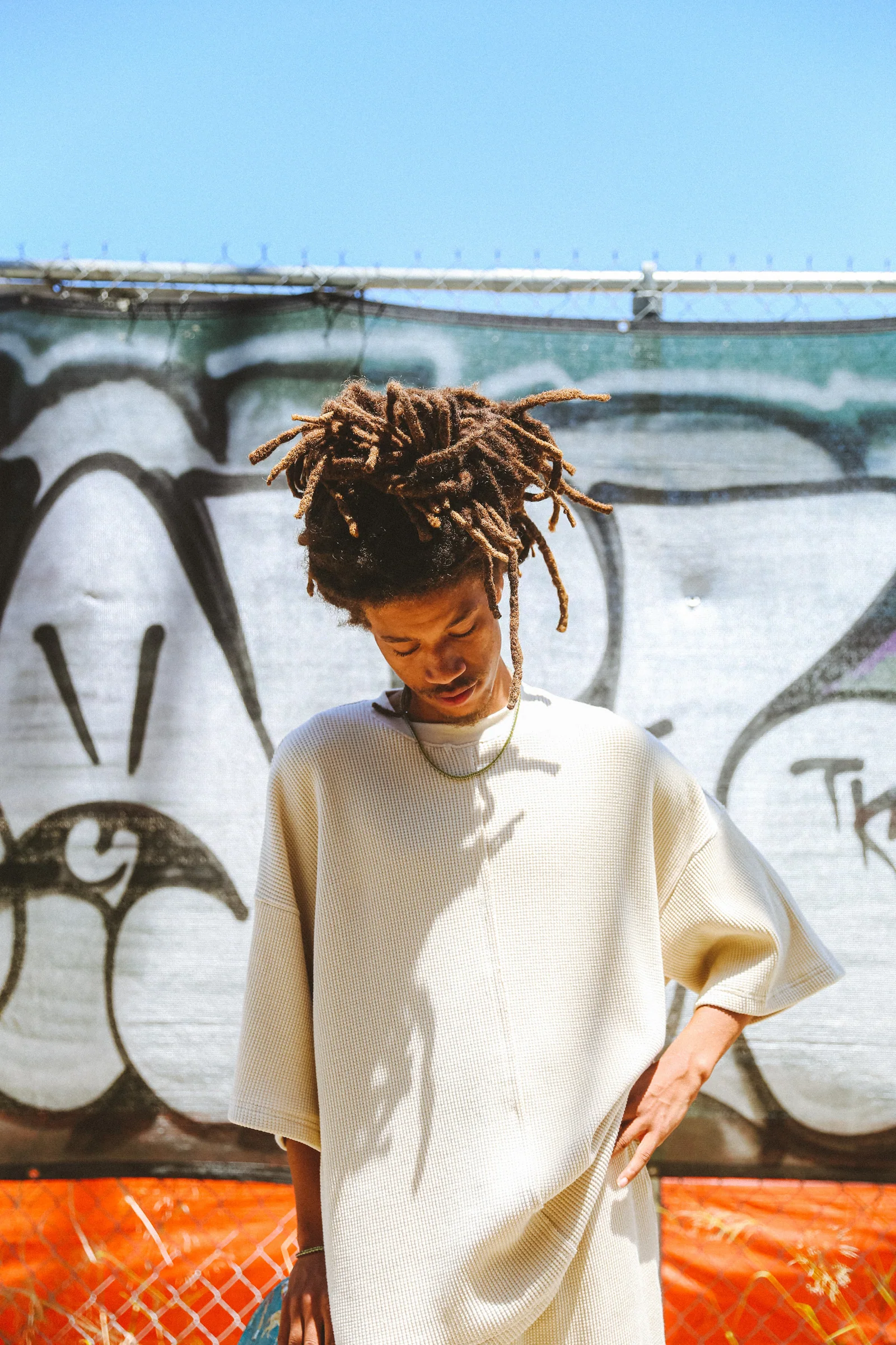 Cannon Mitchel model in a cream top against sunlit street artwork.