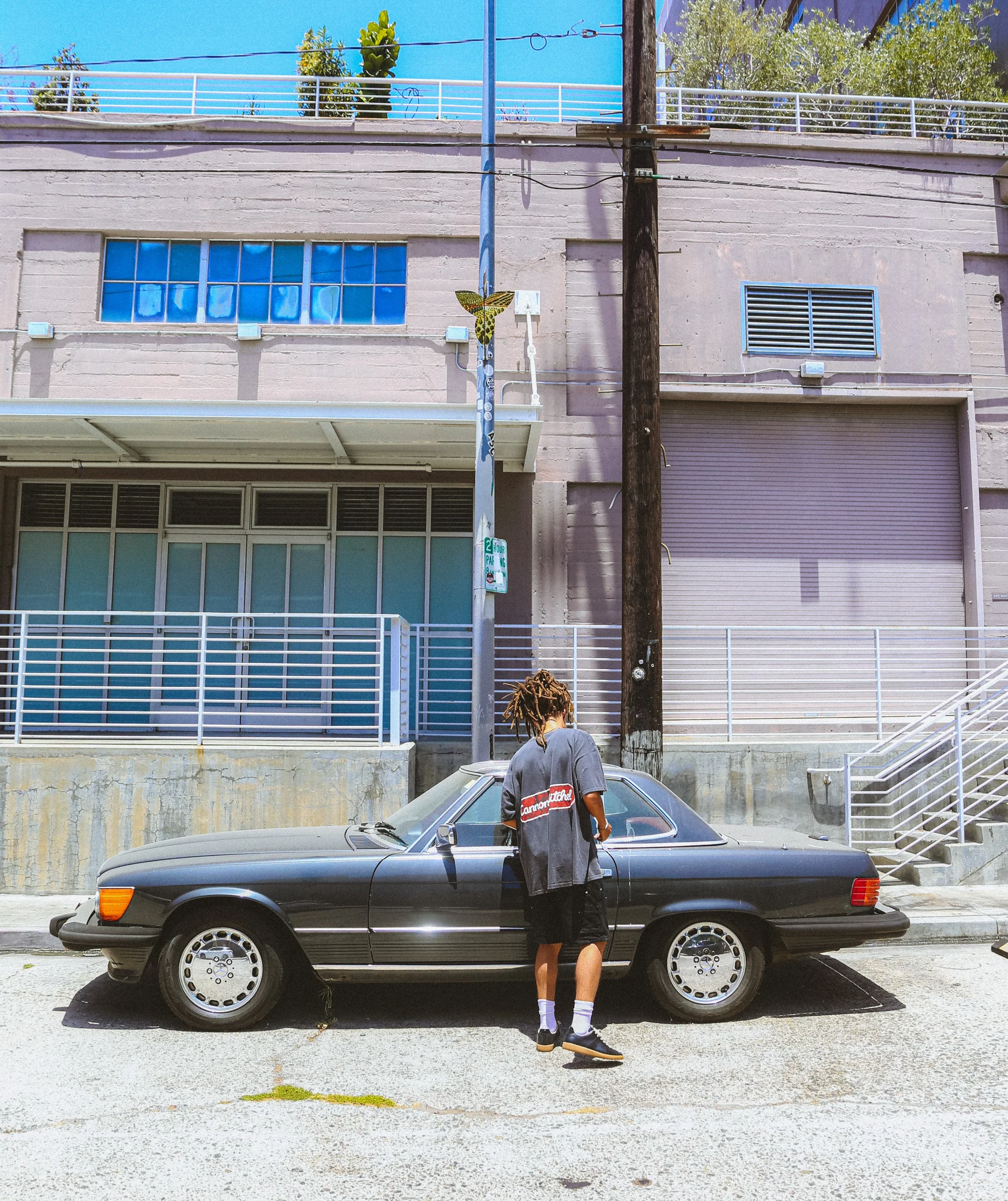 Wide street frame with a Cannon Mitchel model by a parked car.