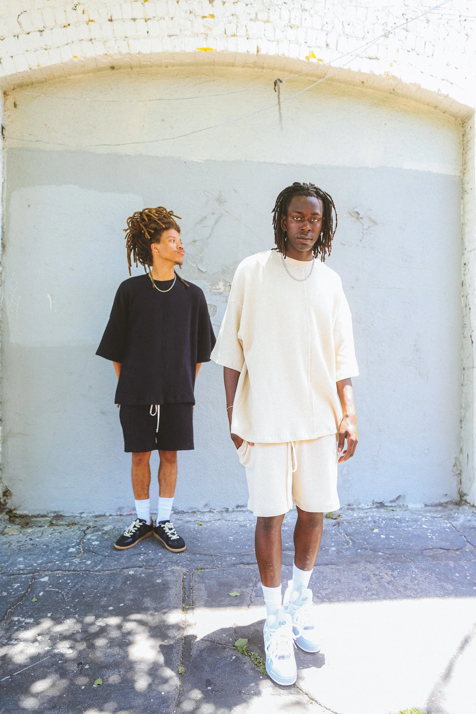 Two Cannon Mitchel models standing together against a pale exterior wall.