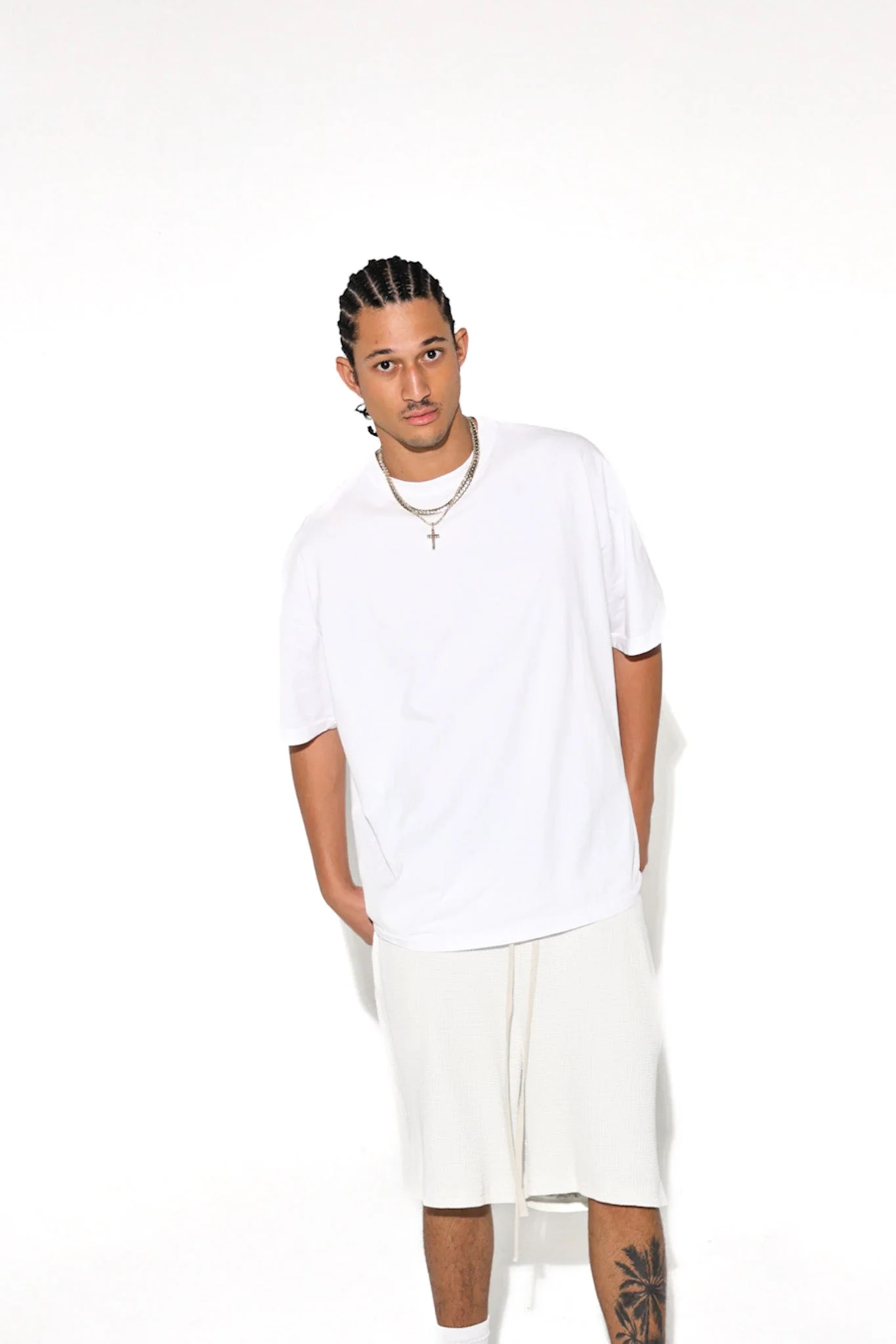 Studio portrait of a model in a white oversized Cannon Mitchel tee and shorts.