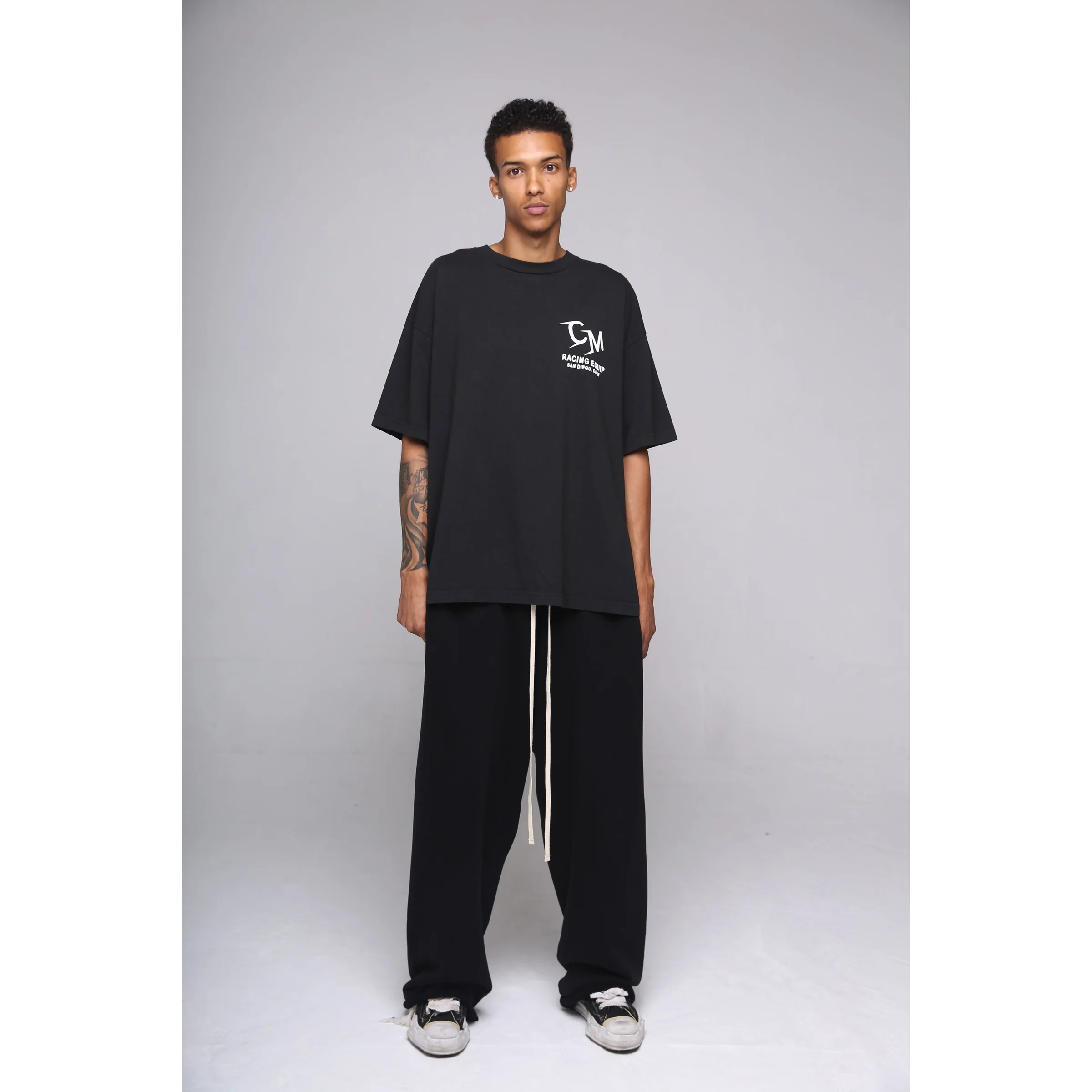 Full studio portrait of a model in a black Cannon Mitchel graphic tee and pants.