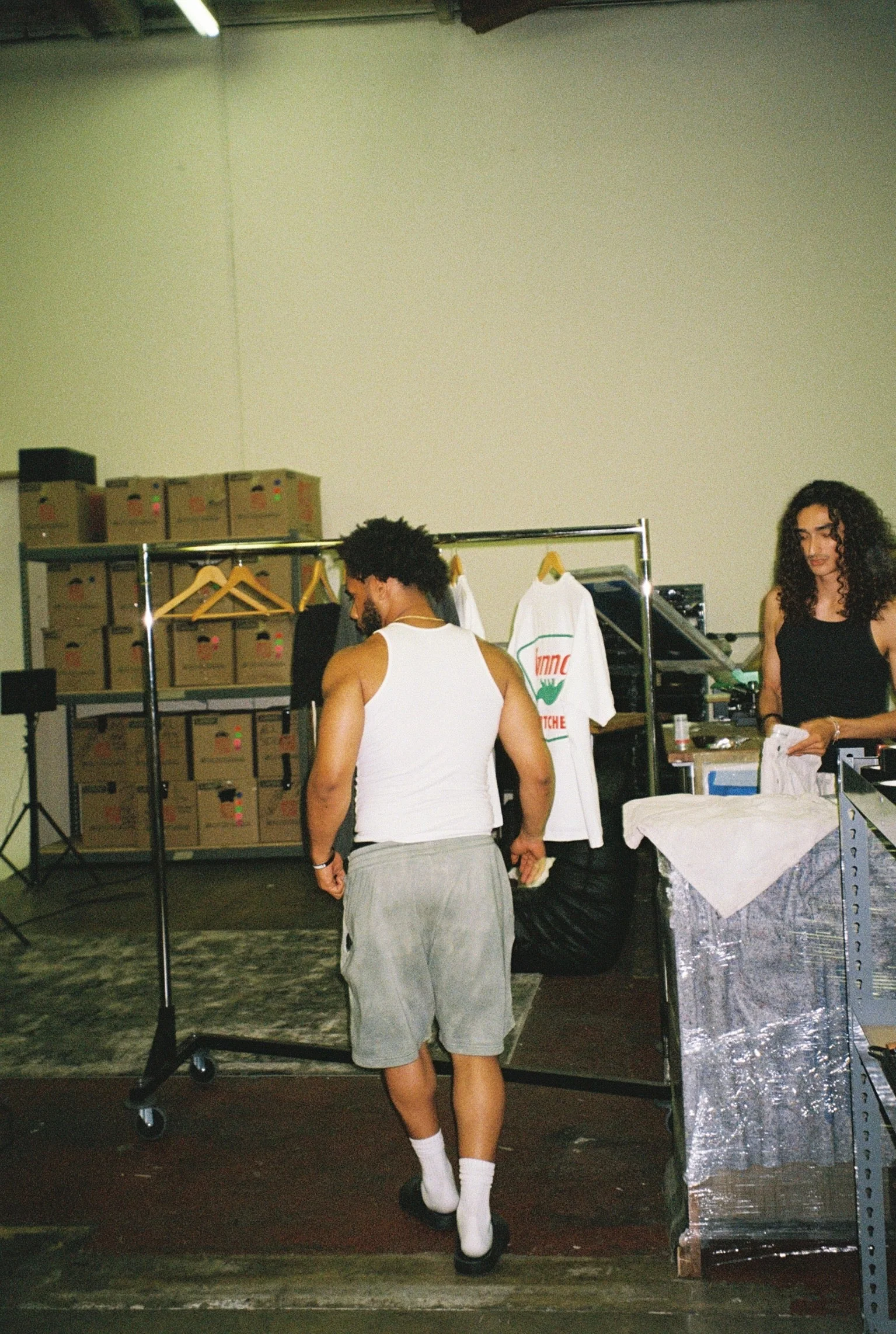 Behind-the-scenes SS26 studio preparation with garment racks and crew.