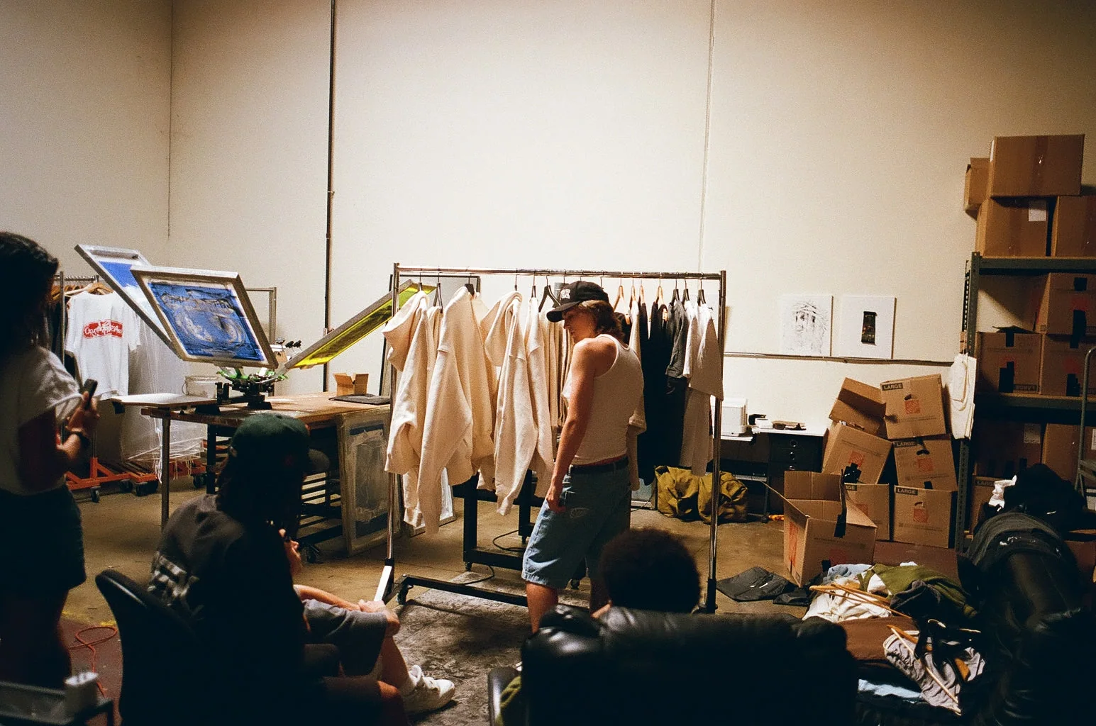 Wide SS26 production room view with garments and studio equipment.