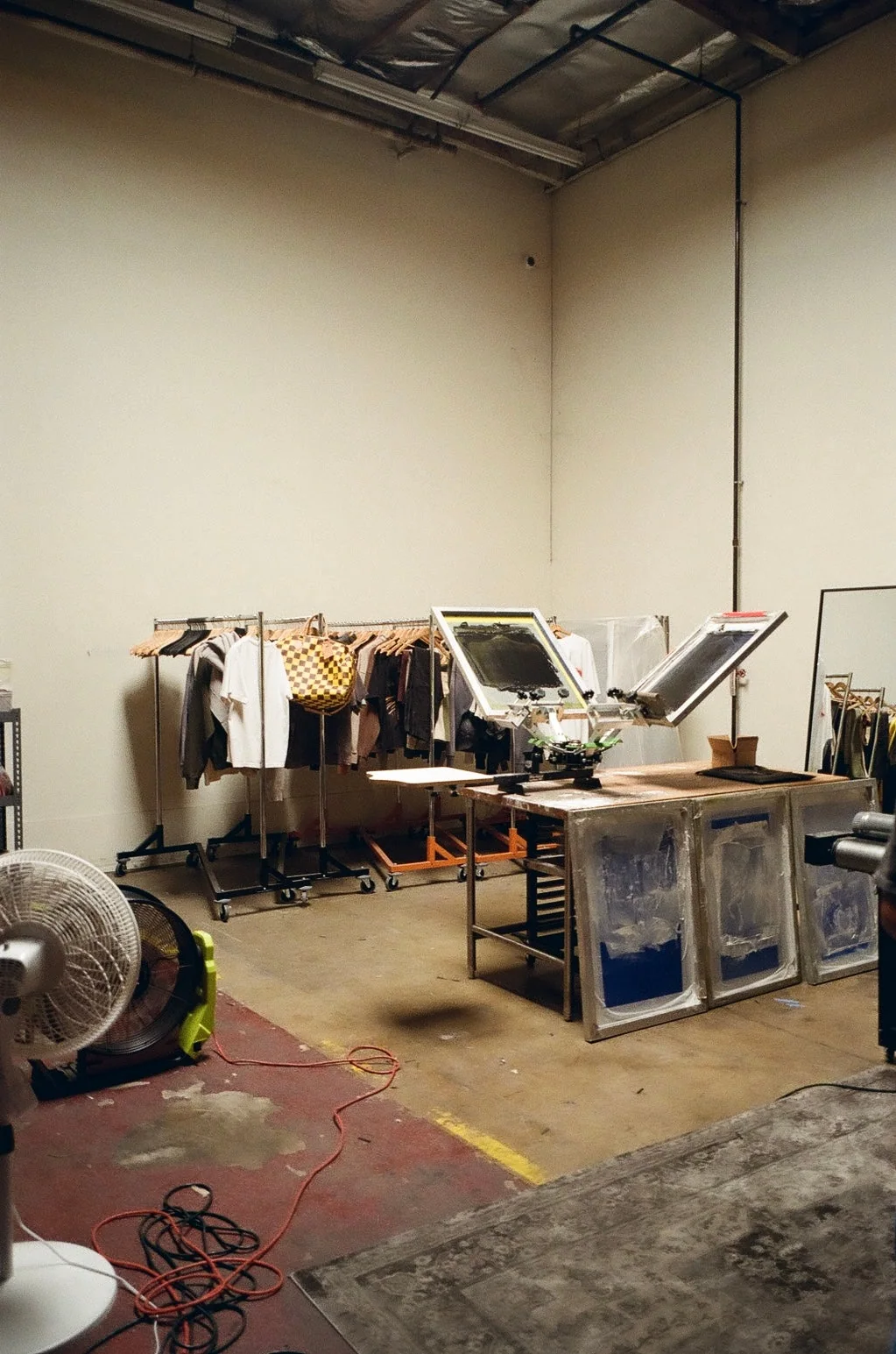 SS26 studio workspace with garments, print equipment, and production floor.